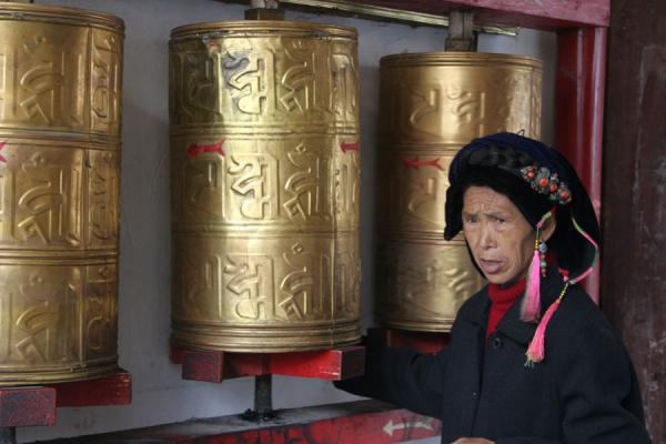 Khampa woman spinning the prayer wheels of a temple in Kangding, China Old Khampa woman spinning the prayer wheels of a temple in Kangding, China