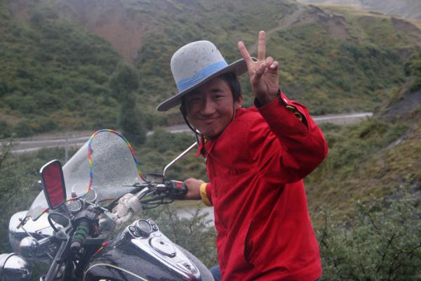 Young Tibetan with common bowler hat on a motorbike, China