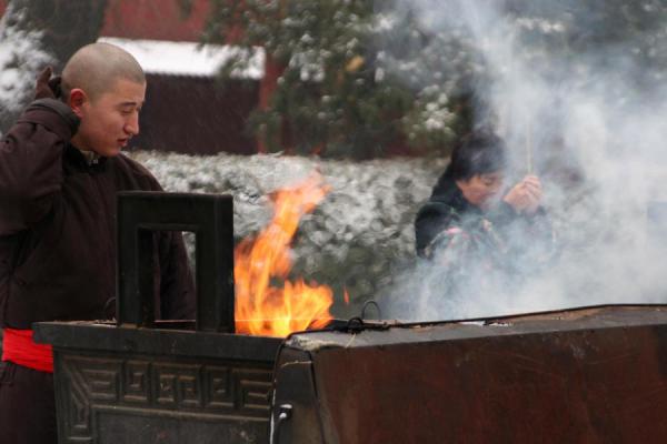 Monk and believer at one of the main incense burners, China