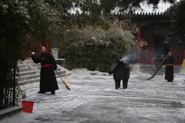 Monk throwing snow in the temple complex, China
