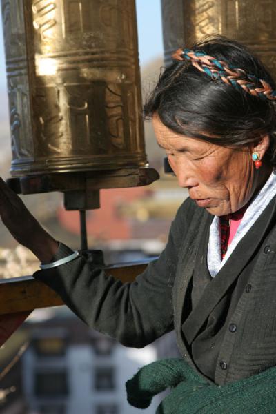 Pilgrim in the early morning making the prayer wheels move, China
