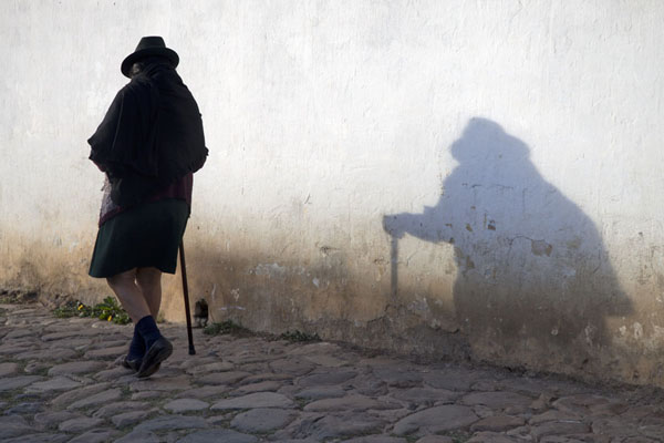 Woman walking past a white wall in Villa de Leyva, Colombia