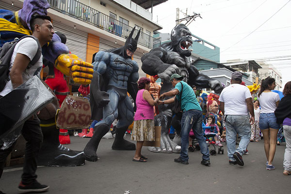 People walking past enormous paper-maché dolls | AÃ±o viejo poppen | Ecuador