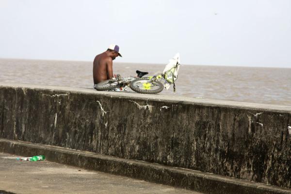 Having a break with a bicycle at the seawall, Guyana