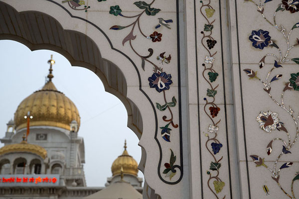 The inlaid arched entrance witht the golden dome of Gurudwara Bangla Sahib in the background | Gurudwara Bangla Sahib | India