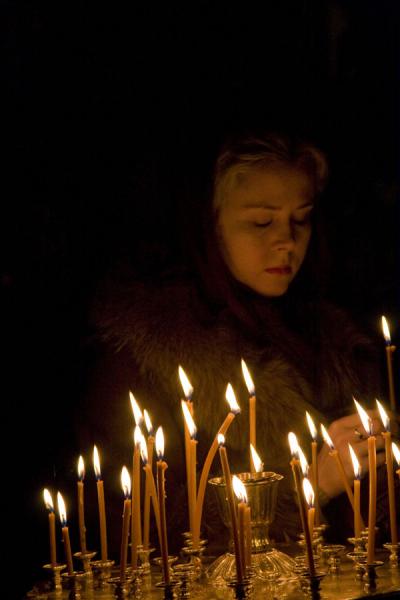 Photo de Woman lighting a candle inside the Cathedral of the Holy AscensionCathÃ©drale de la Sainte Ascension - Kazakhstan
