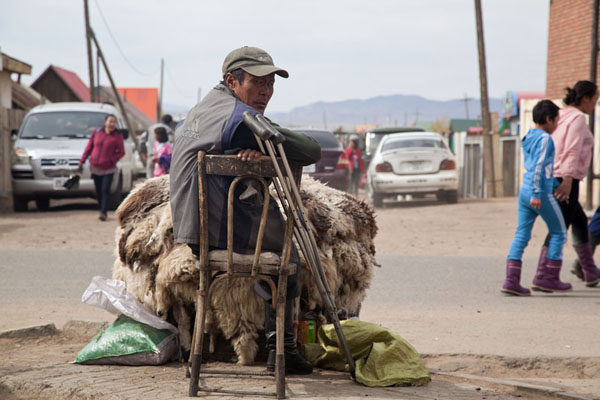 Handicapped man selling sheep skins at a street in Mörön, Mörön, Mongolia