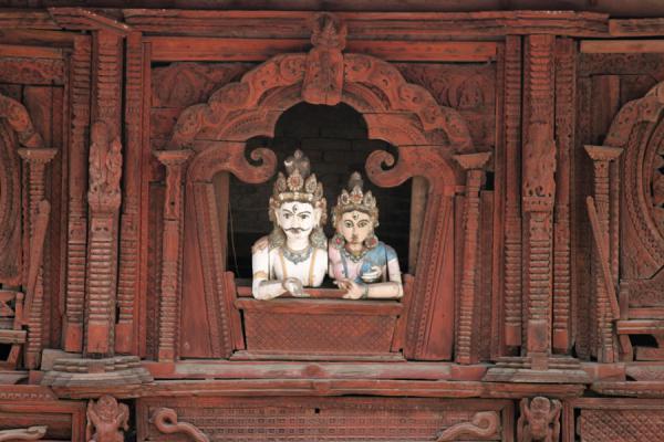 Two statues appearing to look out of a wooden window in the Old Royal Palace | Durbar Square | Nepal