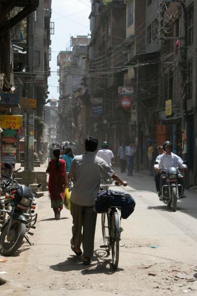 Photo de Man walking a street in Kathmandu with his bikeKatmandou - NÃ©pal