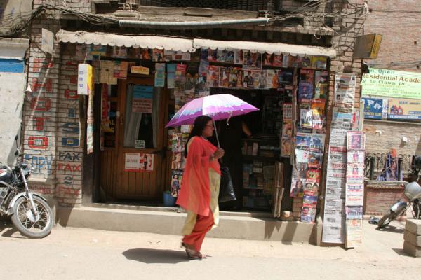 Photo de Woman walking past a shop in Pyaphal ToleKatmandou - NÃ©pal