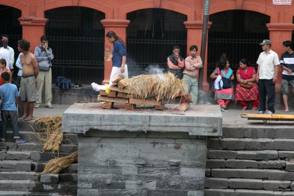 Picture of Smoke starts to billow out of the pyre, the corpse has been covered by strawKathmandu - Nepal