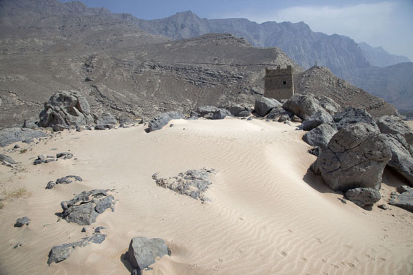 Foto de Stretch of sand and an old watchtower behind, at the top of a hill overlooking the Musandam coastMusandam Peninsula - Oman