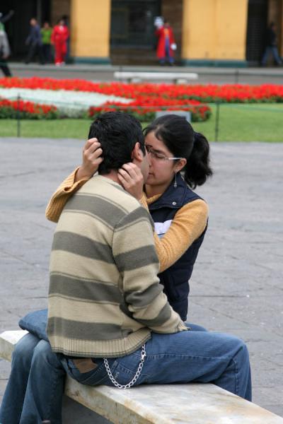 Young romantic couple on a bench of Plaza de Armas, Peru