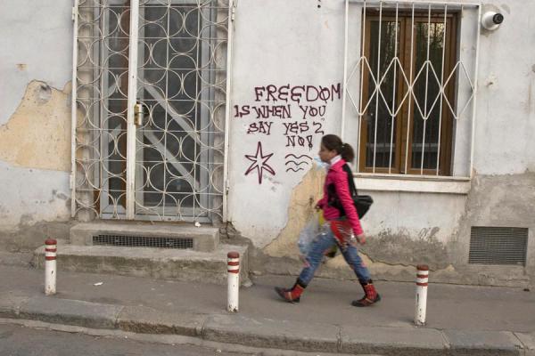Girl walking past a slogan on a wall, Romanian people, Romania