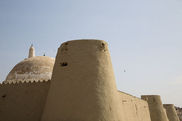 Foto di The adobe wall of Qasr Ibrahim with defensive towers and the dome of Quba mosqueAl Hofuf - Arabia Saudita