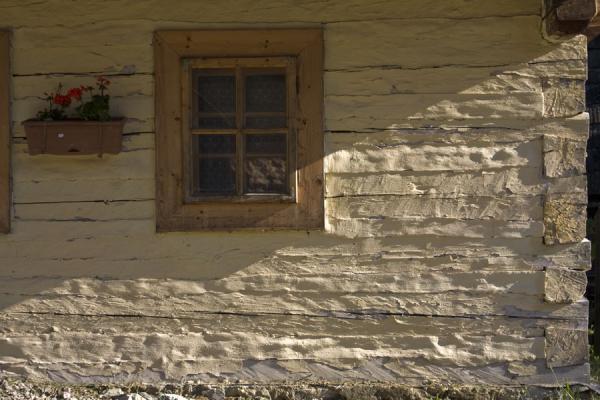 Window and flowers on the painted façade of a log house in Vlkolínec | Caminata Cervino | Suiza