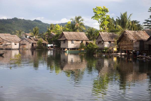 Foto van Salomonseilanden (Typical houses of the village of Lilisiana reflected in the tranquil waters of the river)