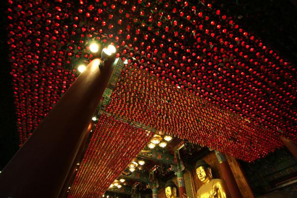 Inside Jogyesa temple: golden Buddha statues and lights from the ceiling, South Korea