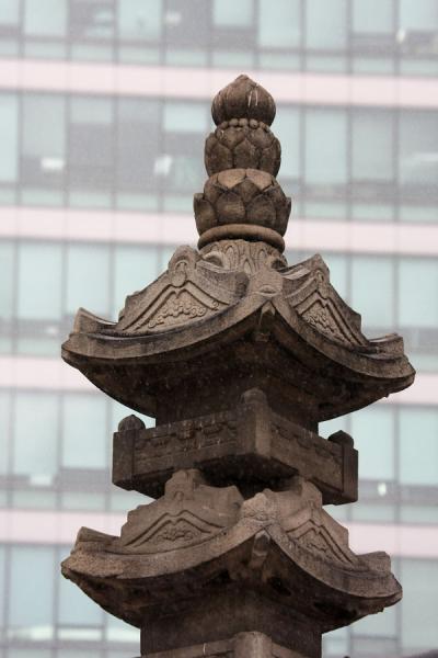 Top of seven story stone pagoda with modern building at Jogyesa temple, South Korea