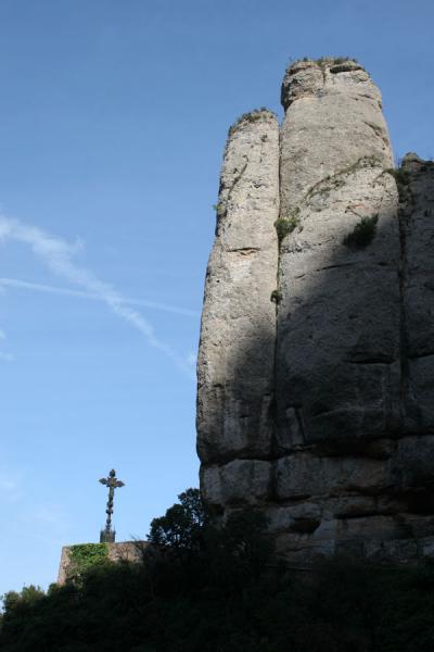 Steep cliffs rising above an iron cross in the mountains of Montserrat, Spain