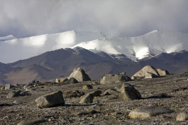 Boulders contrasting with the snow-capped mountains surrounding Lake Kara Kul | Lago Kara Kul | Tagikistan